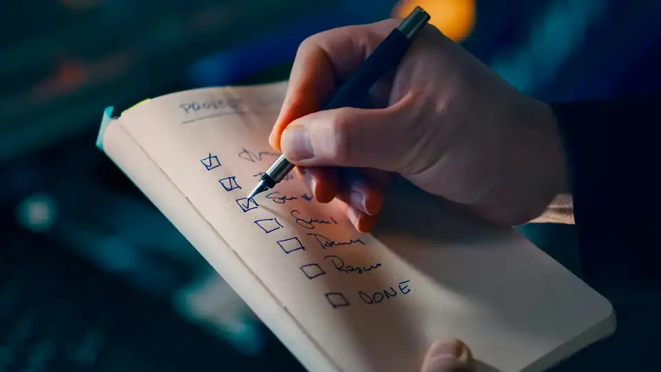 Hand checking off items on a to-do list in a notebook