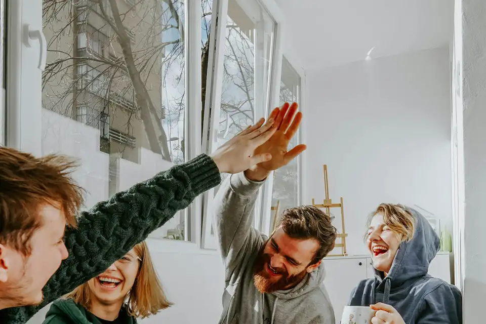 Four friends laughing over coffee at home