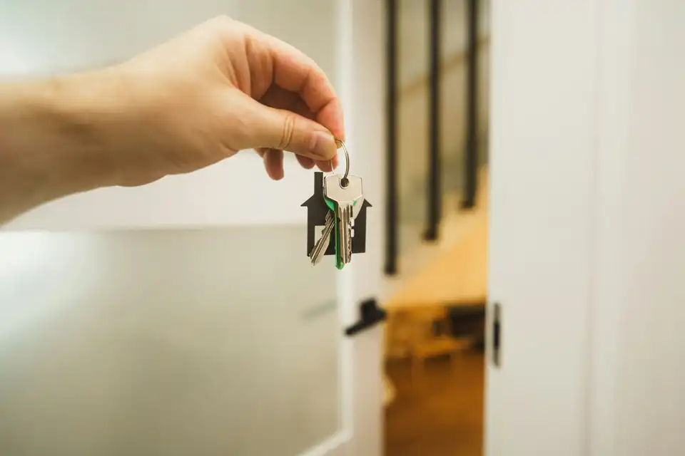 Hand holding keys in front of an open door