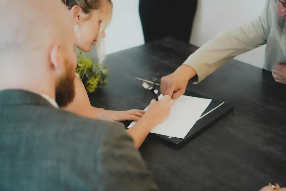 Couple signing a document at a desk with an adviser